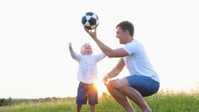 快乐的父亲和他的儿子在操场上玩球