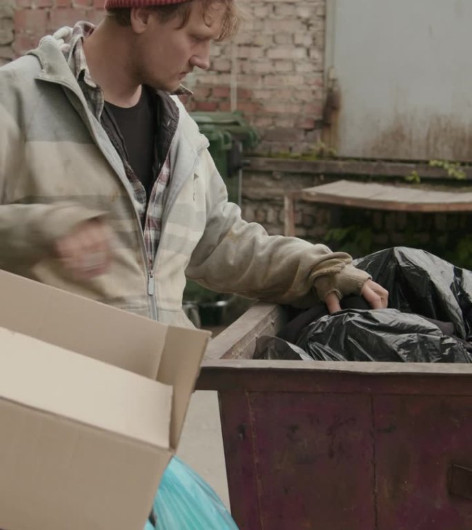 衣衫褴褛的乞丐在装满垃圾的容器里挖土