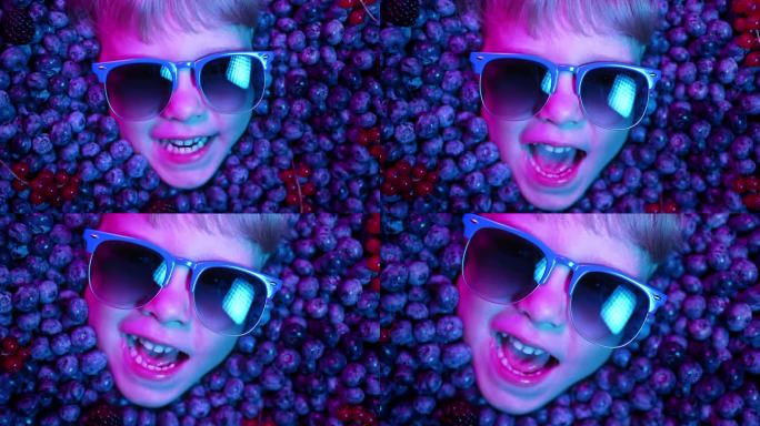 男孩的脸上挂着新鲜成熟的浆果——蓝莓、草莓、红醋栗。小惊奇的孩子满身黑莓。孩子们在示威。维生素，抗氧