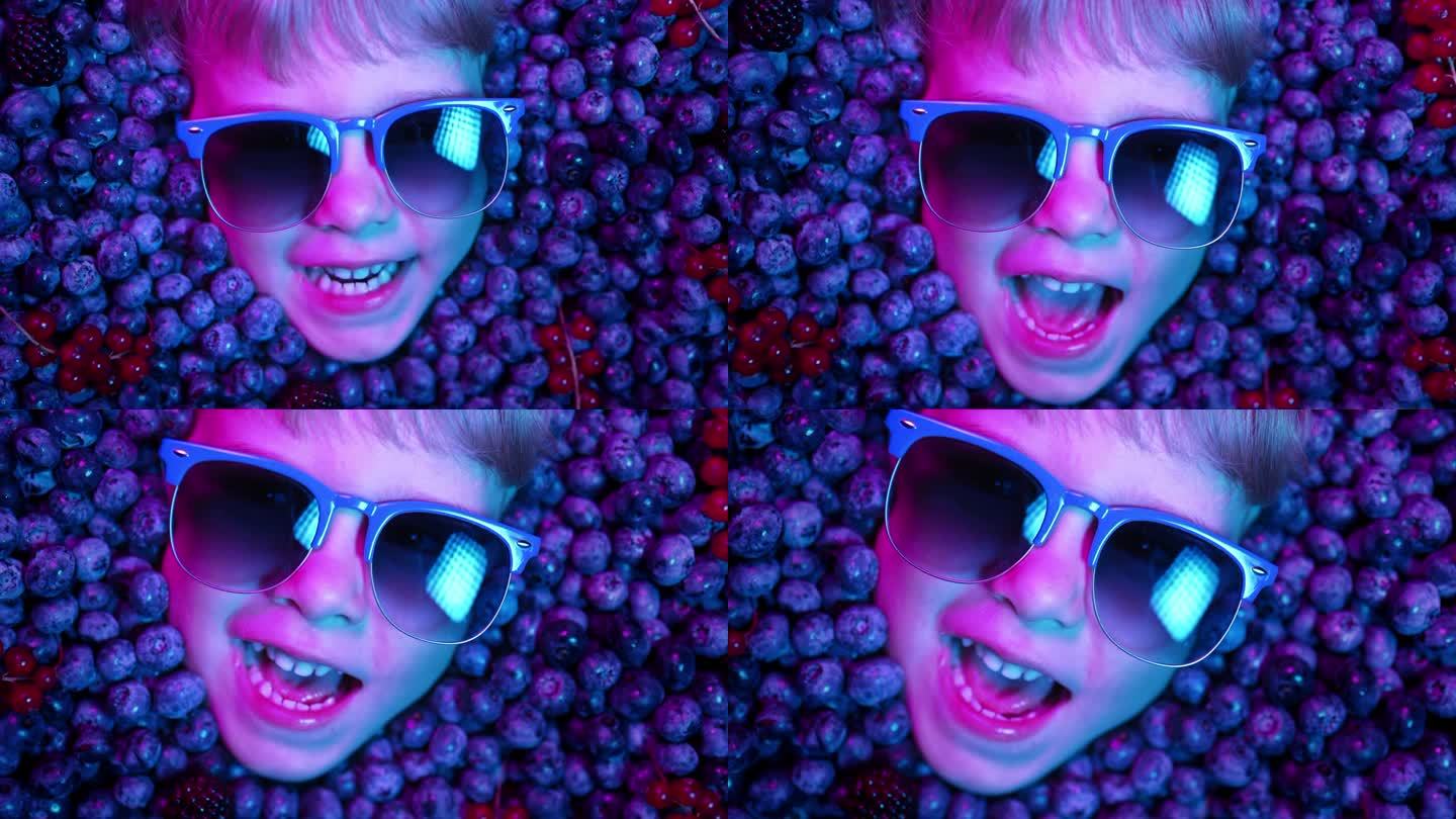 男孩的脸上挂着新鲜成熟的浆果——蓝莓、草莓、红醋栗。小惊奇的孩子满身黑莓。孩子们在示威。维生素，抗氧