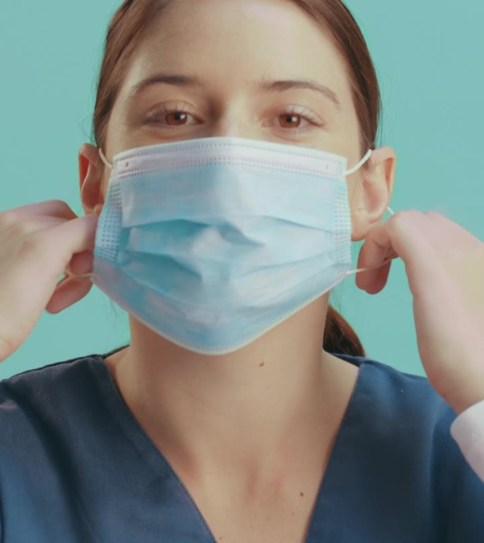 戴口罩的女性、面部或护士在演播室背景下摘下口罩，用于医疗保健、健康和防细菌。微笑、快乐或医生在医院诊