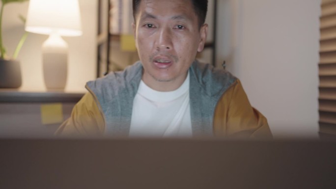深夜，戴着眼镜的亚洲男子用笔记本电脑查看和搜索文件、数据合同