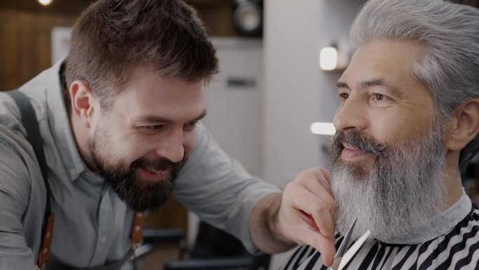 专业理发师在理发店用剪刀为优雅成熟的男士修剪胡须