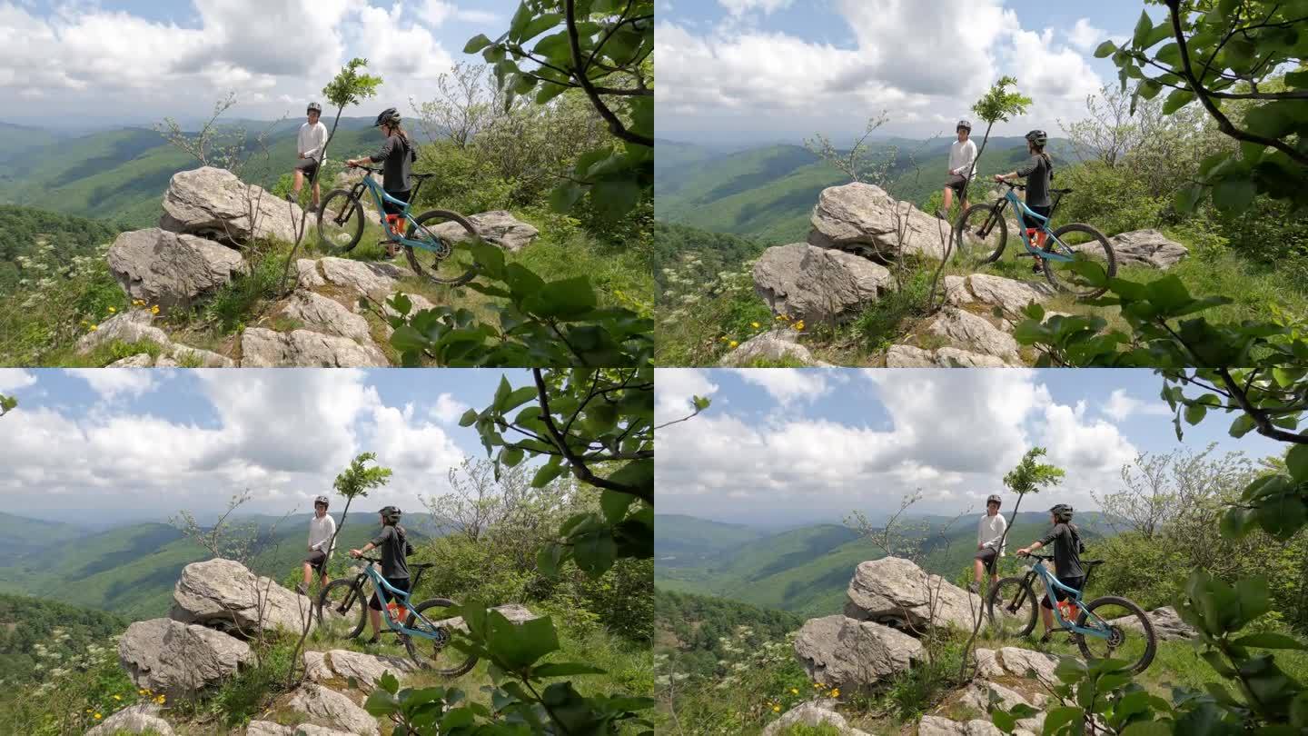 山地自行车手推着自行车俯瞰山谷、森林