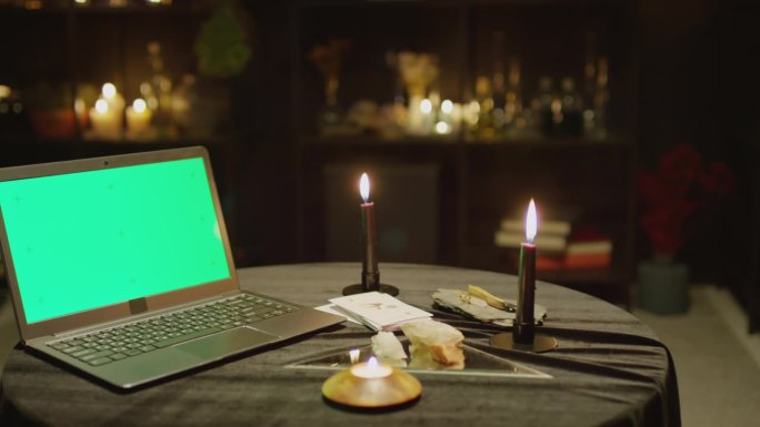 笔记本电脑与彩色键屏幕上的桌子与燃烧的蜡烛