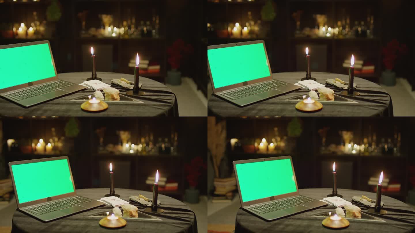 笔记本电脑与彩色键屏幕上的桌子与燃烧的蜡烛