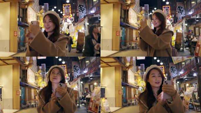 图为，一名亚洲女性在傍晚游览日本大阪的筑天阁塔。她用智能手机捕捉每一刻，记录她在热门景点的旅行经历。