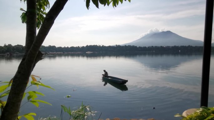 面目全非的湖上船夫操纵着他的木排船渡过湖面。树遮住了视野。模糊了