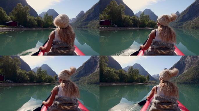 一个美丽的女人在一个原始的湖上划桨穿过山脉的后视图