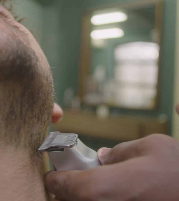 理发师用电动剃须刀剃男性脖子的手