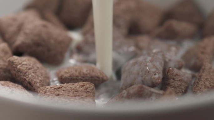 慢镜头特写:早餐用麦片巧克力枕头把牛奶倒进碗里