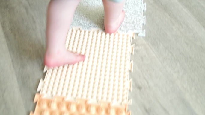 孩子们的脚走在由各种形状和触感的拼图制成的矫形按摩垫上。草，球果，橡子-纹理细节。预防和治疗扁平足