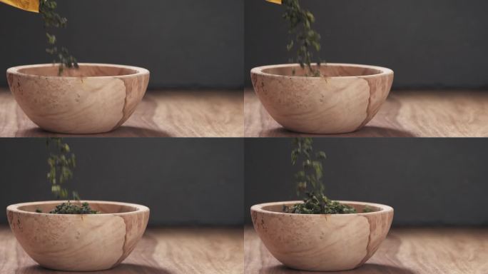 慢动作将干绿乌龙茶倒入木碗中，摆上有复制空间的木桌