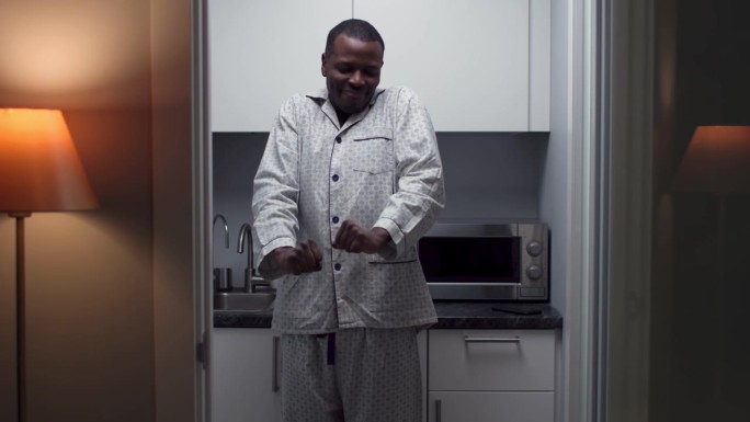 昏昏欲睡的非洲裔美国人一大早站在厨房里打哈欠伸懒腰