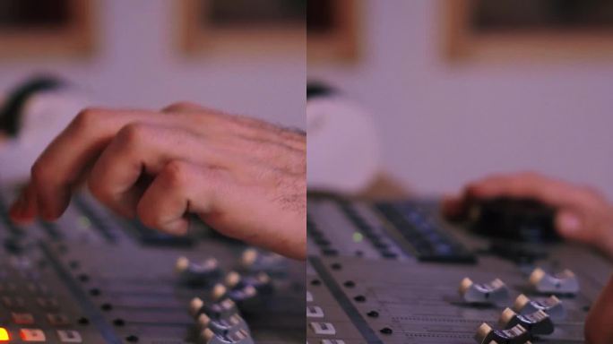 在录音、广播或音乐制作的混音控制台工作的手的垂直特写肖像。工程师使用工作室音频混频器旋钮和调频器。音