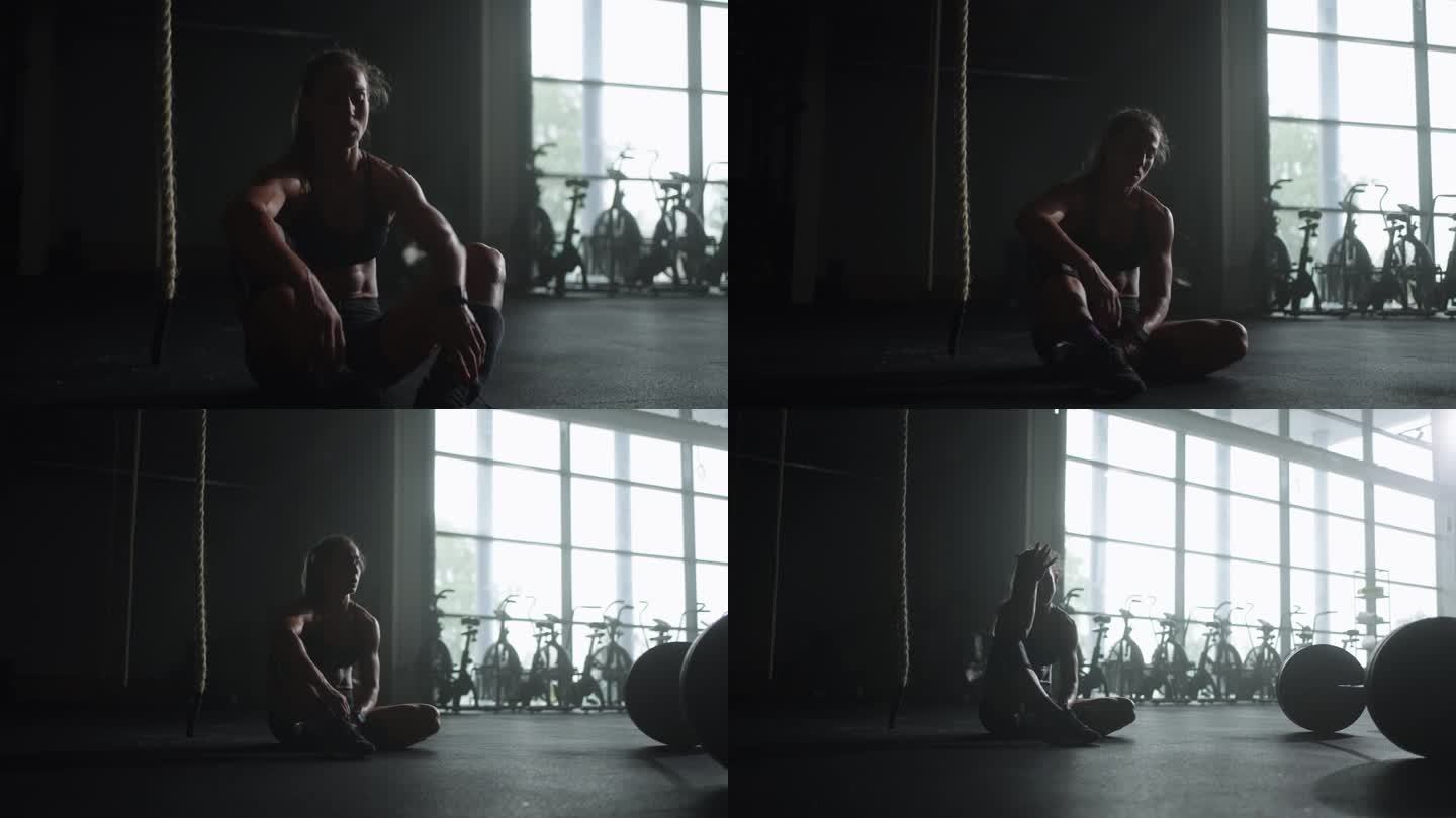 精疲力竭的女运动员在高强度训练后，呼吸困难，坐在健身房地板上