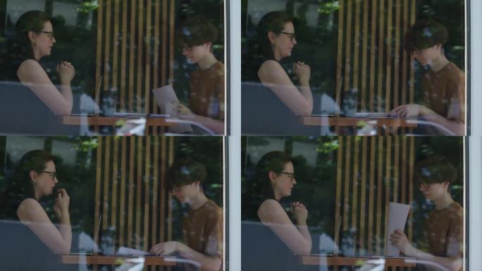 女人在咖啡馆里和年轻的男学生说话，透过窗户看窗外，手里拿着报纸
