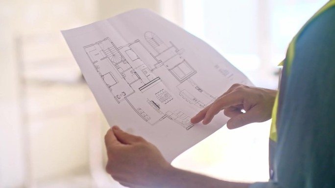 专业建筑师的手指着手里的公寓设计方案图纸
