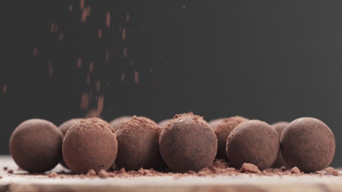 用慢镜头特写，将巧克力松露撒上可可粉