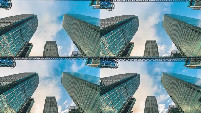 英国伦敦金丝雀码头大楼内，低角度拍摄的高层企业大楼与云层反射的摩天大楼和玻璃电梯