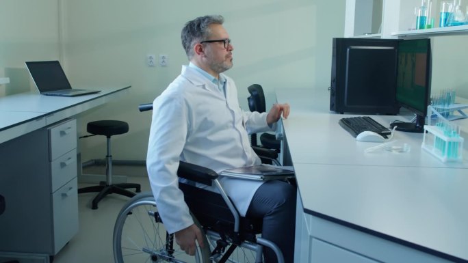 坐在轮椅上的男科学家在办公桌前工作