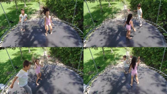 在一个大后院，一个6岁的小女孩和一个5岁的小男孩在蹦床上欢快地玩耍。绿色的草地和树木为他们提供了一个