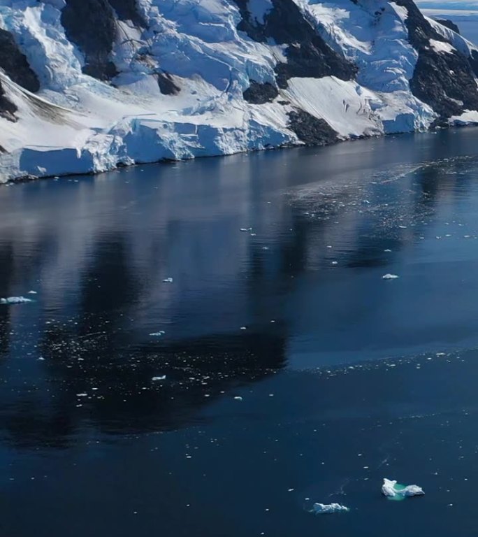 垂直镜头令人惊叹的景观雪山在南极海洋。
