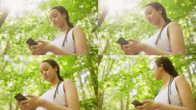 一个女人用手机上的全球定位系统在森林里导航