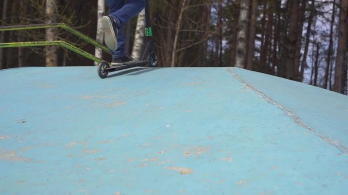 一个快乐的男孩在滑板公园骑着特技滑板车。