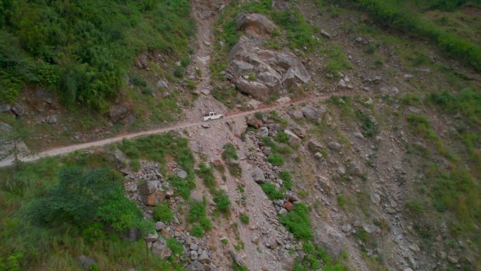 空中静态视图白色卡车车辆与旅游团在通往马南的山路上行驶。公路旅行在喜马拉雅山脉的安纳普尔纳山脉。去尼