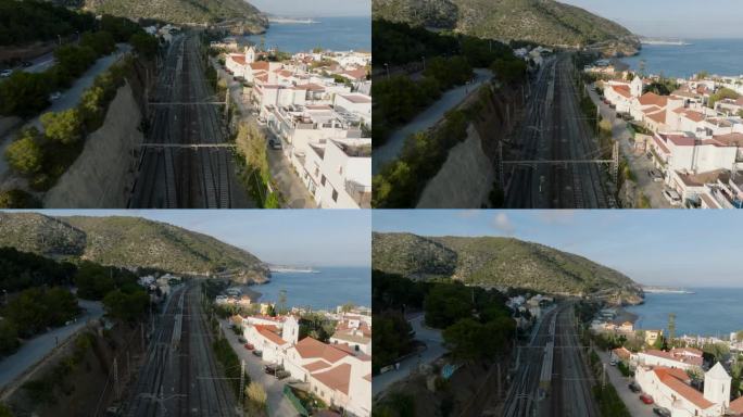 前方飞过多轨铁路线，穿过沿海小镇。场景中的阴影和直射阳光。Garraf、西班牙