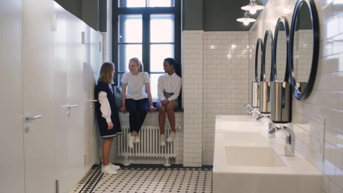 多民族少女女友在课间休息时在学校洗手间聊天