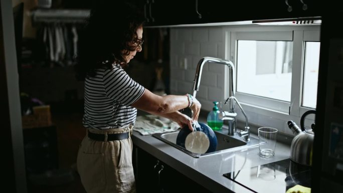 在厨房洗盘子的中年西班牙妇女