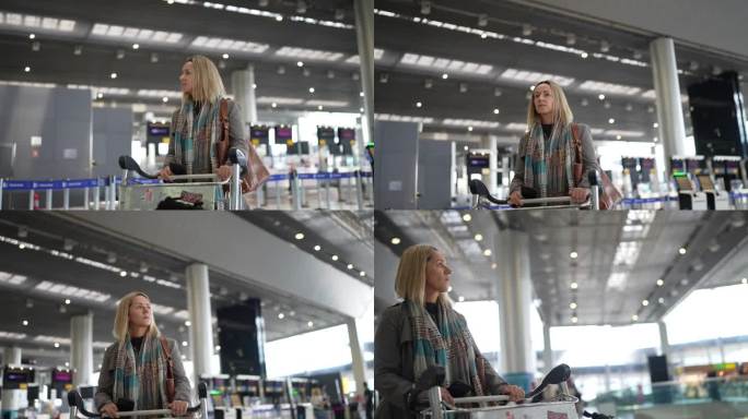 成熟的女人在机场推着行李车走