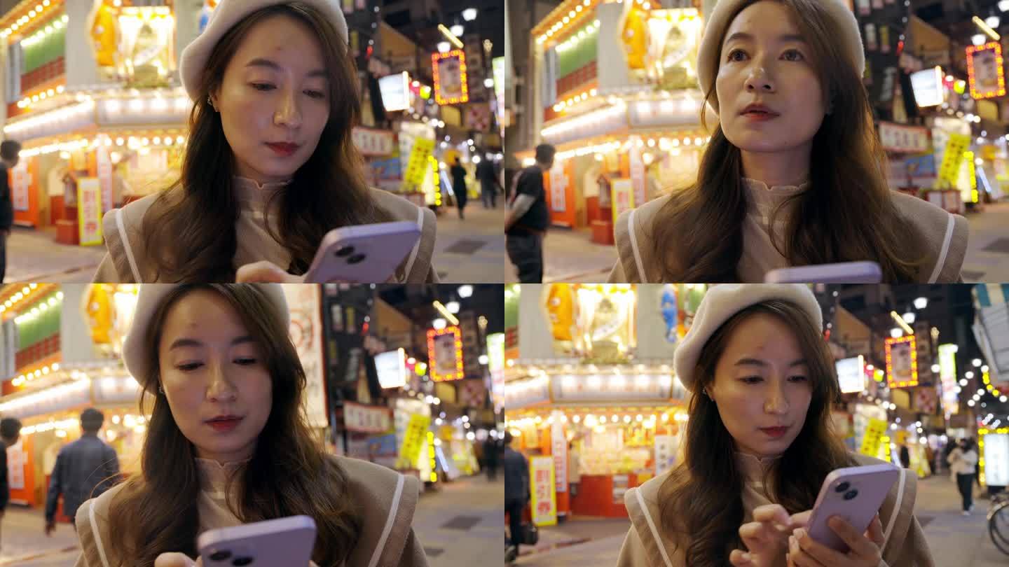 一位亚洲妇女正在日本大阪观光。晚上，她发现自己来到了标志性的筑天阁塔，用智能手机应用程序导航到她想去