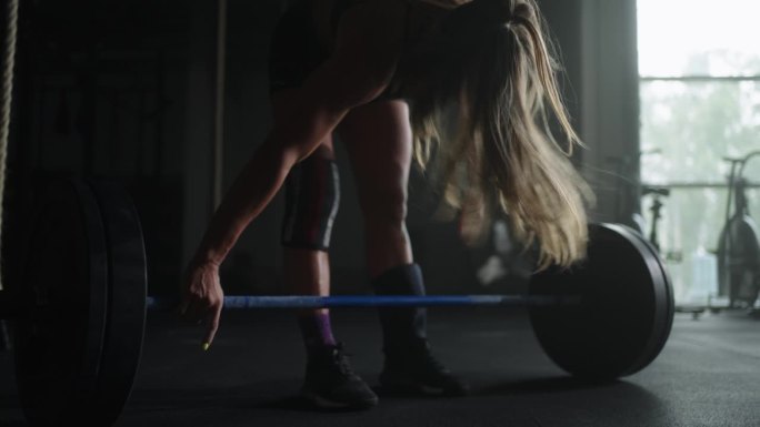 女运动员在健身房举杠铃前服用镁粉，运动女性的轮廓