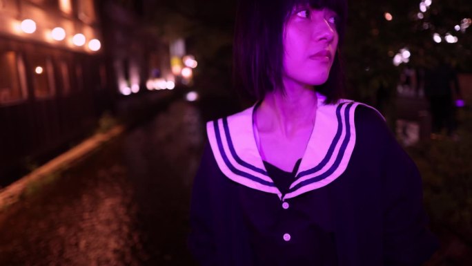 女人站在桥上等人在城市的夜晚，在紫光下