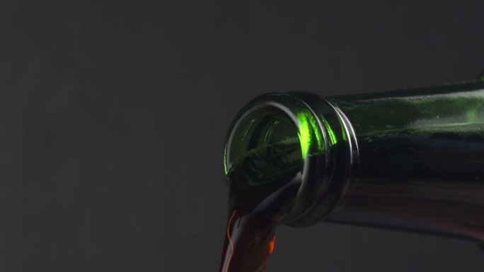 慢动作宏观黑啤从绿色的瓶子倒出来
