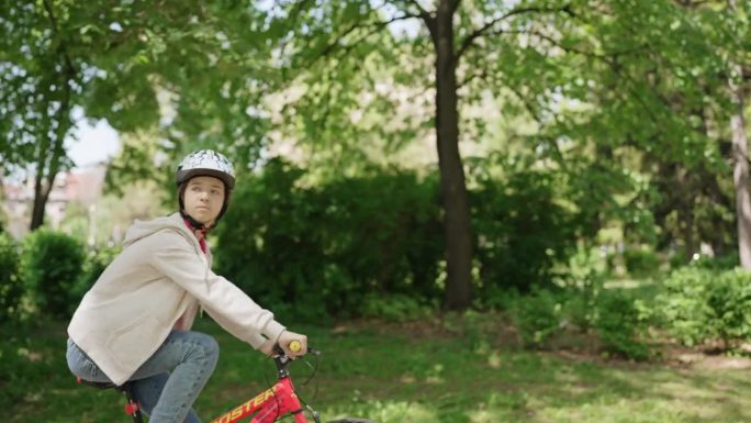 一个十几岁的女孩戴着头盔在公园里骑自行车