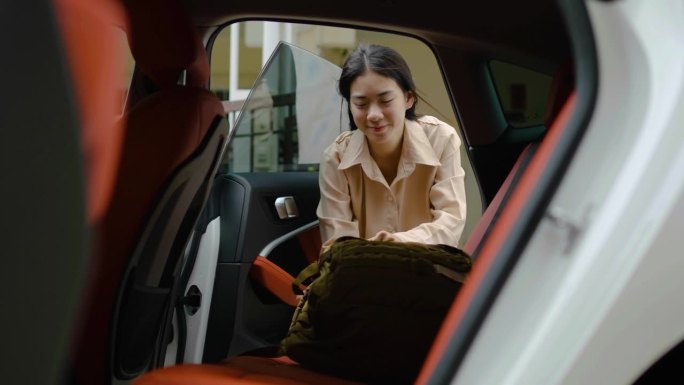 快乐的年轻亚洲女游客打开车门，把他的背包、旅行箱、旅行包和瑜伽垫放在后座上，装上一辆车，准备一次旅行
