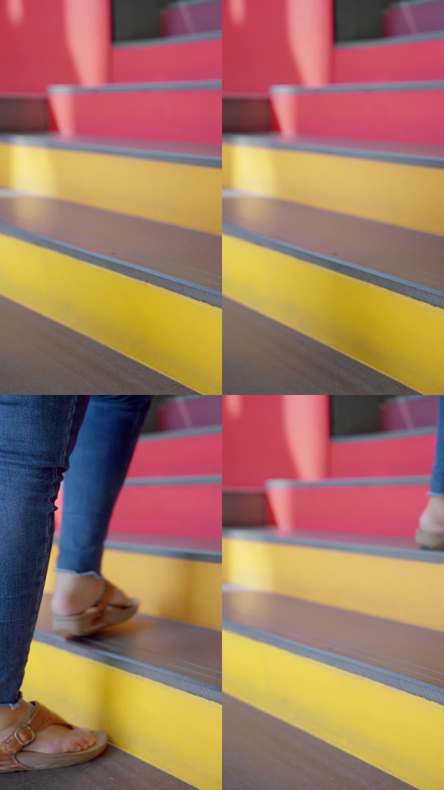 一个不知名的女人穿着牛仔裤和凉鞋走上彩色的红黄相间的梯子