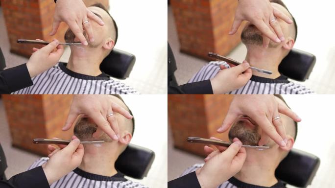 理发店里，理发师正在用一把老式直刀给顾客刮胡子。经典剃须用不锈钢直刃剃刀