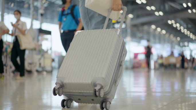 拖着行李箱走向机场登机口的女旅客