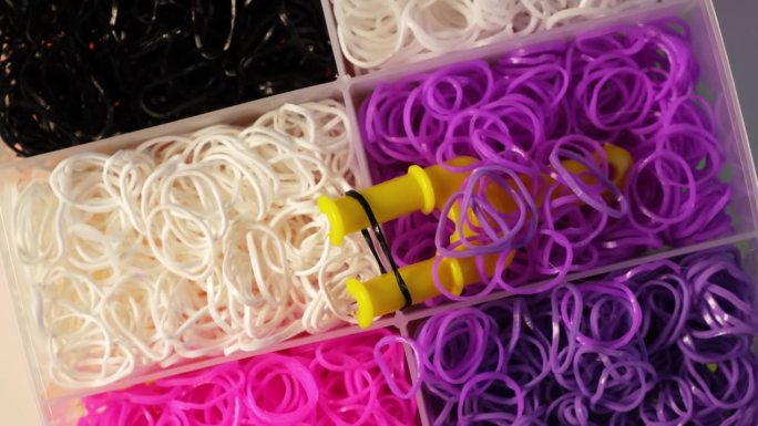 织布机带套件各种颜色，钩针钩和夹子在塑料盒，俯视图。橡皮筋填充织机套装。孩子手链制作工具包。4K视频