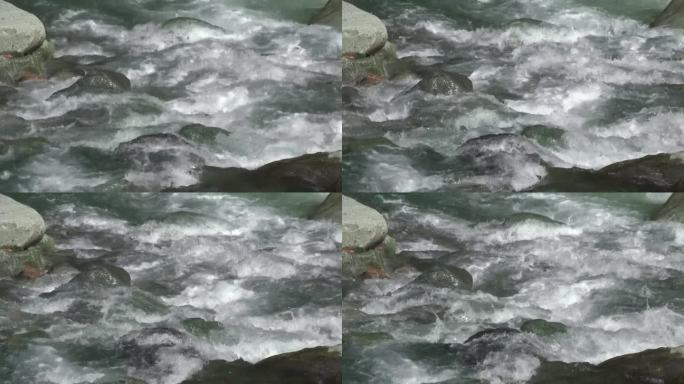 泡沫般的溪水在河床上圆形的椭圆形石头之间流动