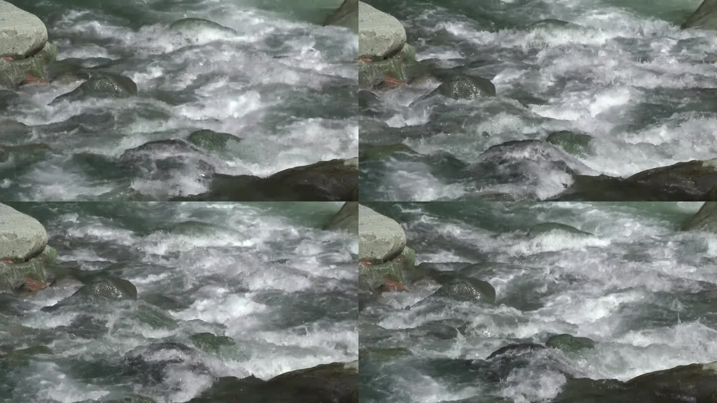 泡沫般的溪水在河床上圆形的椭圆形石头之间流动