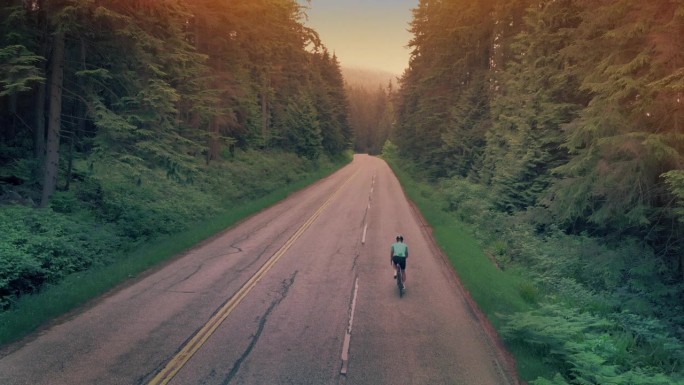 男子在日落时骑自行车上路，耐力概念
