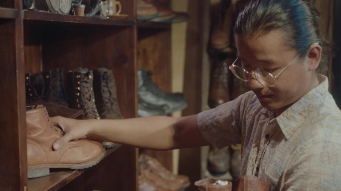 亚洲古董卖家将旧靴子放在古董店的货架上