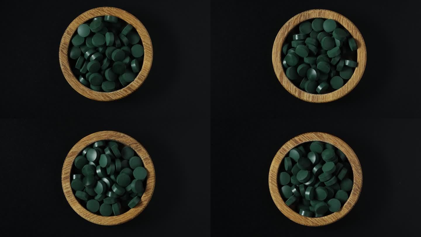 绿色的螺旋藻药丸在木制的碗在黑暗的背景。4K视频，旋转。海藻萃取物的压片在替代医学中被广泛使用