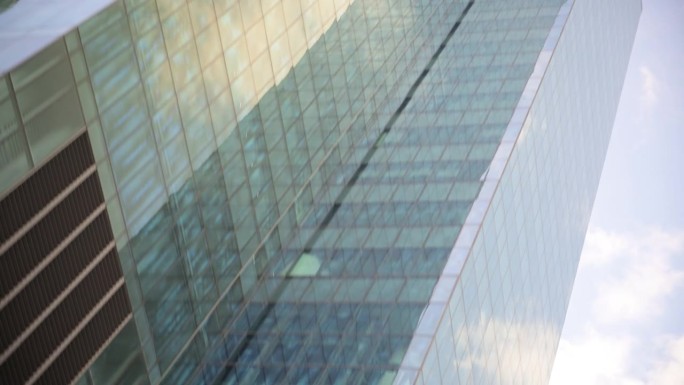 蓝天白云映照在城市的大型蓝色玻璃办公楼里